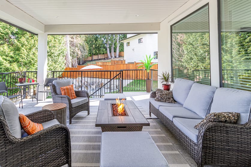 A luxurious spacious deck with stylish patio furniture with a fire pit table heater