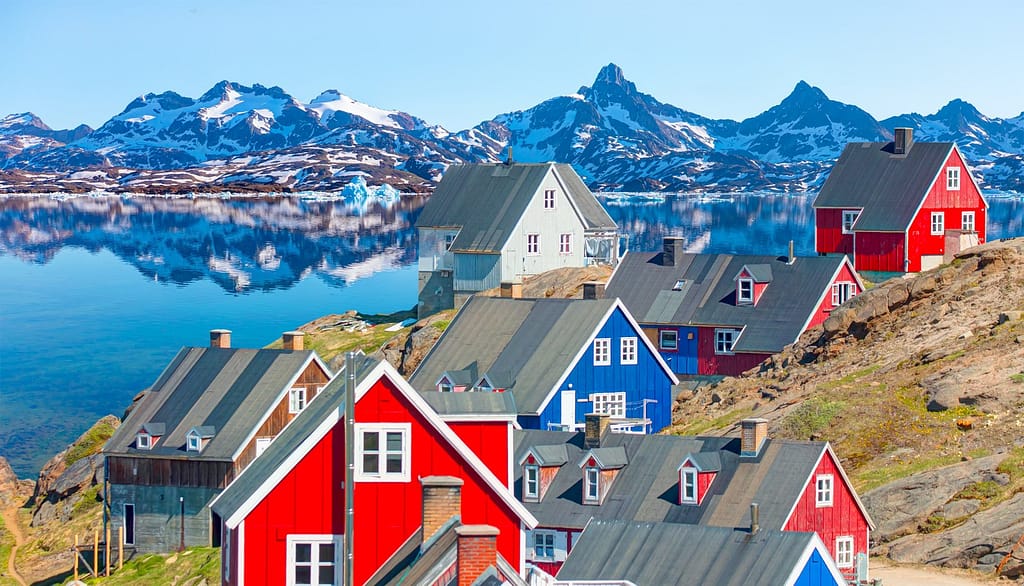 Village on coast of Greenland with houses in deep blue and red